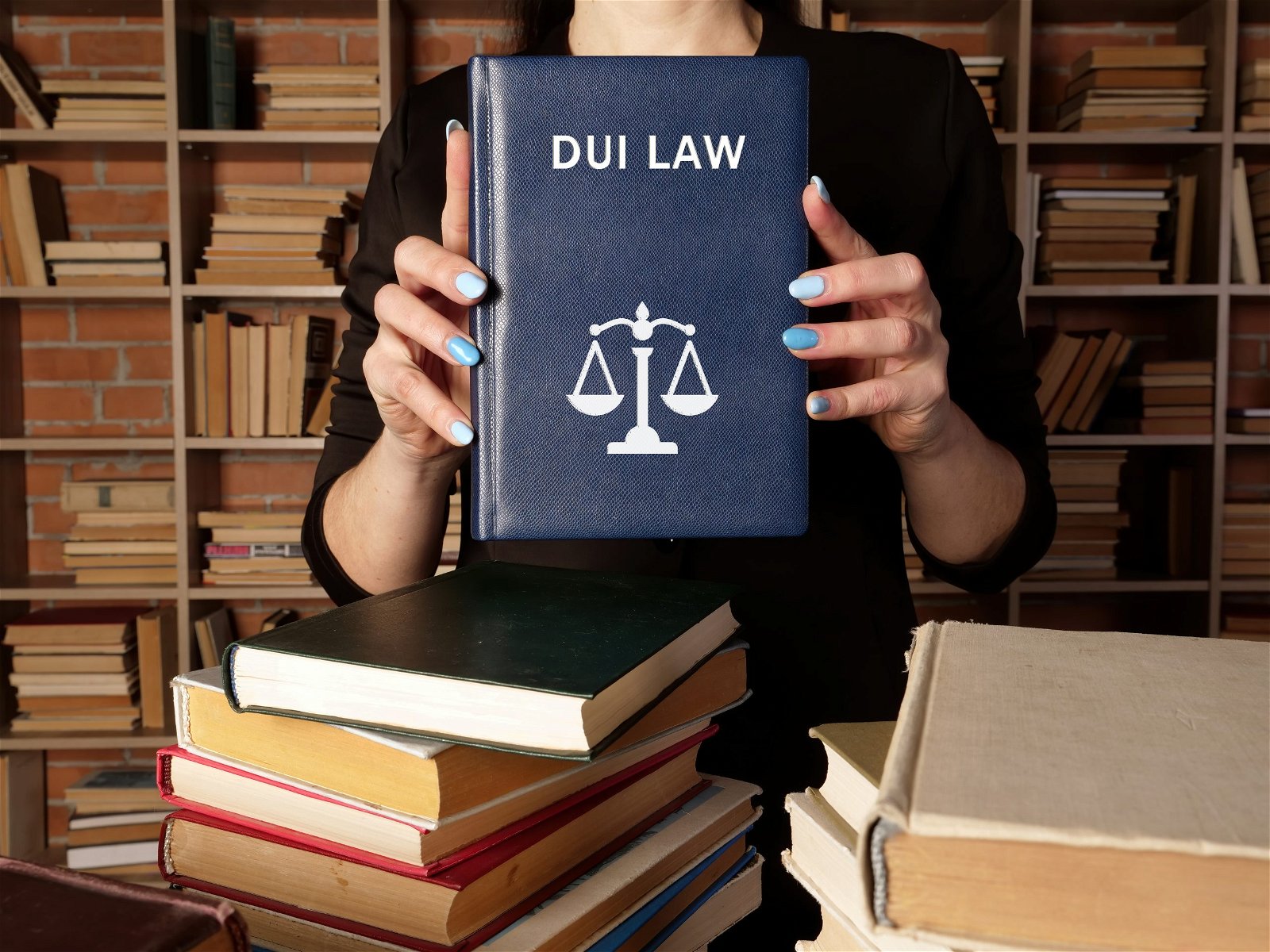 Lawyer holds DUI LAW book. Among other names, the criminal offense of drunk driving may be called driving under the influence